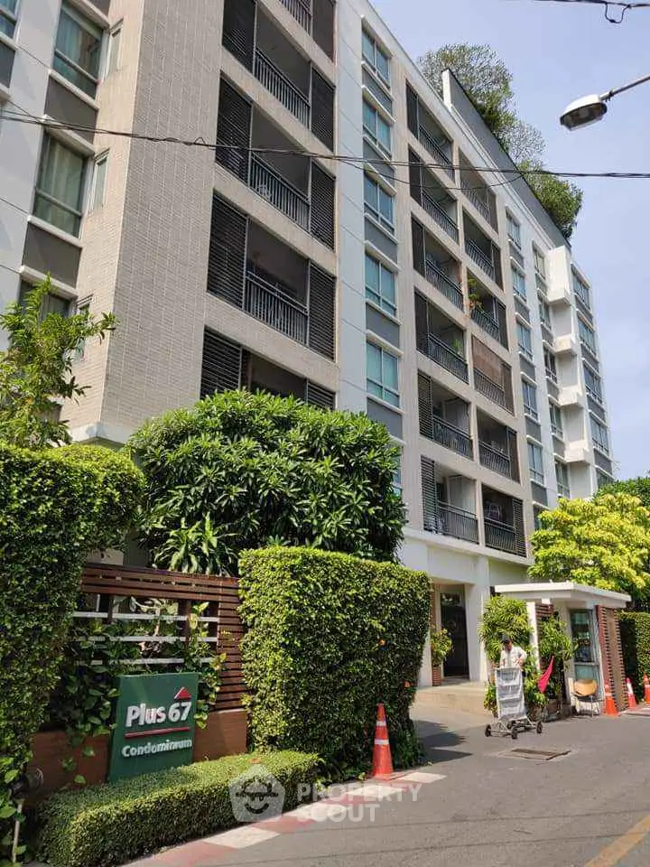 Modern condominium building with lush greenery and secure entrance in urban setting.