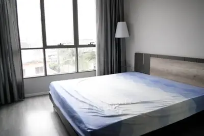 Spacious bedroom with large window and modern decor in urban apartment.
