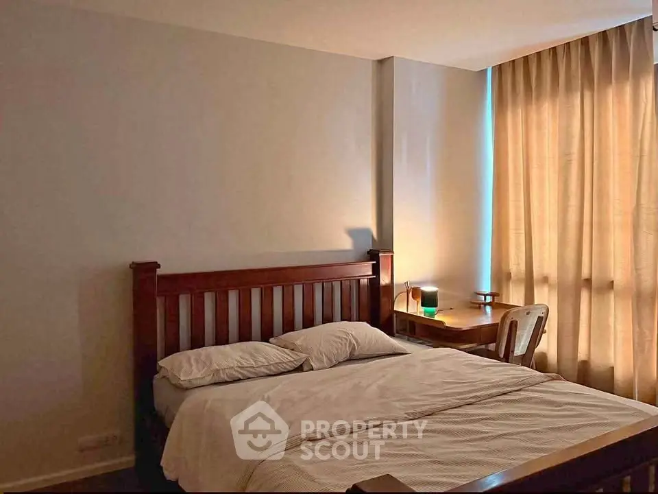 Cozy bedroom with wooden bed frame and natural light through curtains.