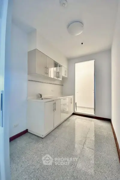 Modern minimalist kitchen with sleek white cabinets and granite flooring