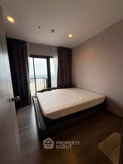 Spacious bedroom with large window offering stunning city views, perfect for relaxation and comfort.