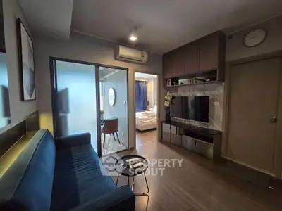 Modern living room with sleek furniture and view into cozy bedroom