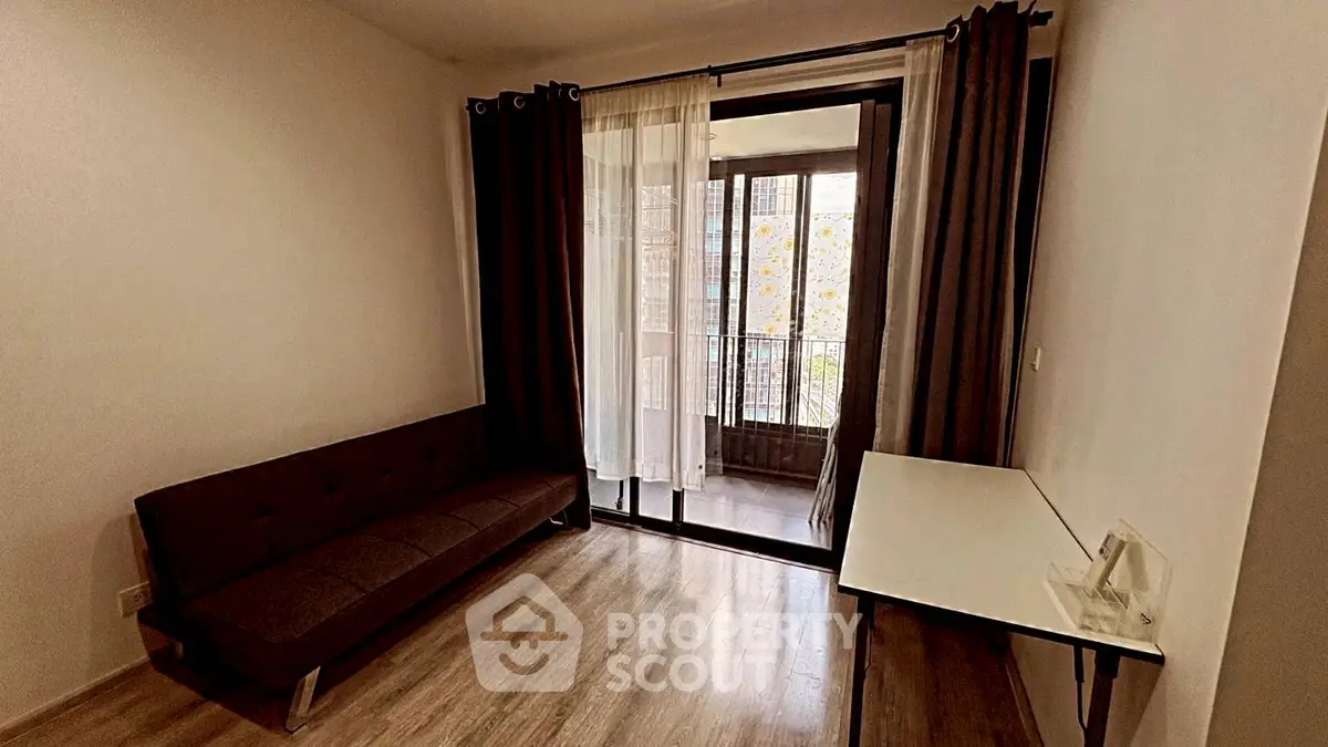 Cozy living room with modern sofa and balcony access, perfect for relaxation and natural light.
