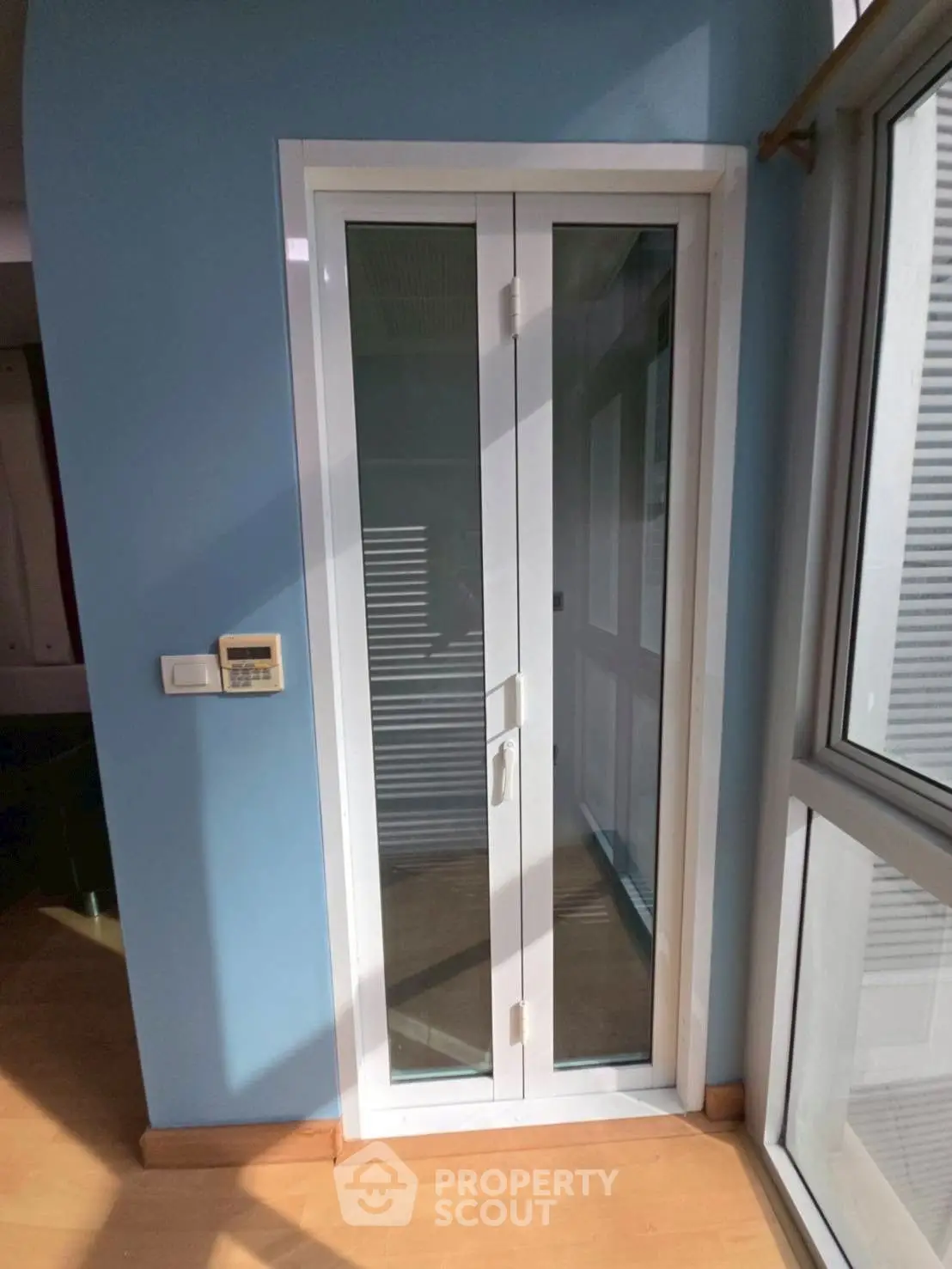 Modern interior with glass door and blue walls, showcasing natural light and sleek design.