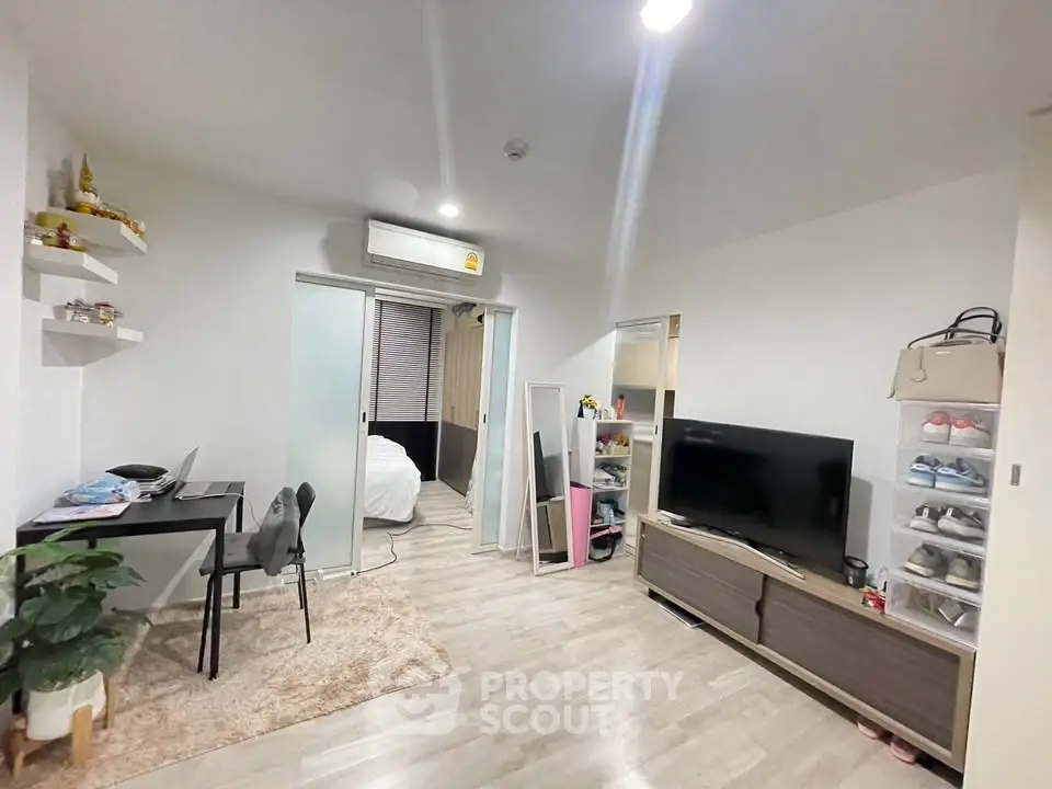 Modern living room with sleek furniture and open layout, featuring a cozy workspace and stylish decor.
