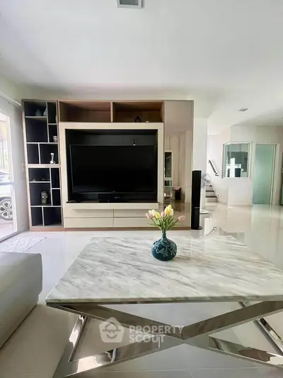 Modern living room with sleek marble table and large TV unit, perfect for stylish entertaining.