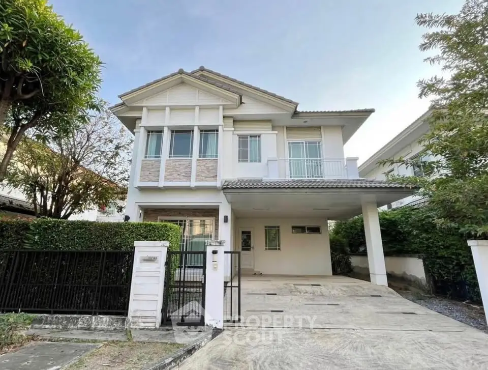 Charming two-story house with spacious driveway and lush greenery, perfect for family living.