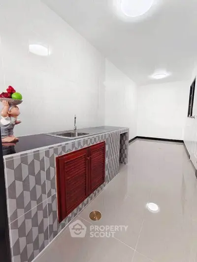 Modern kitchen with sleek countertop and unique tile design, featuring ample space and contemporary fixtures.