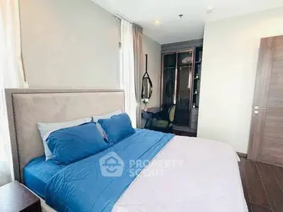 Modern bedroom with blue bedding and stylish decor in a contemporary apartment.