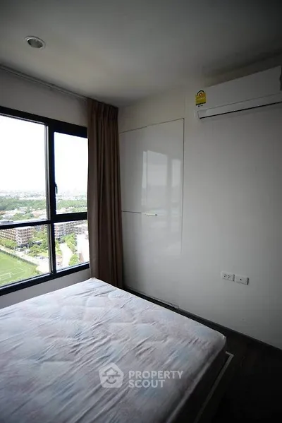 Cozy bedroom with large window offering stunning city views and modern air conditioning unit.