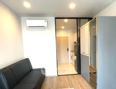 Modern living room with sleek design and sliding glass door leading to a compact kitchen.