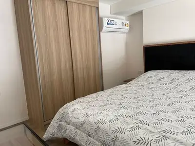 Cozy bedroom with modern wooden wardrobe and air conditioning unit.