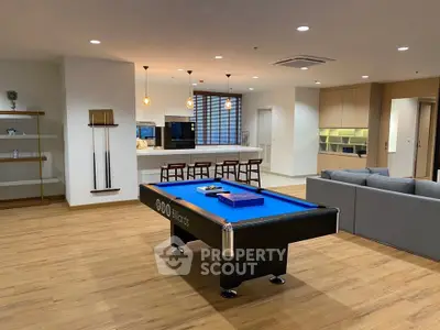 Spacious modern living room with pool table and open kitchen layout, perfect for entertainment.