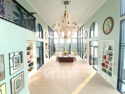 Luxurious living room with high ceilings, elegant chandelier, and expansive windows offering stunning views.