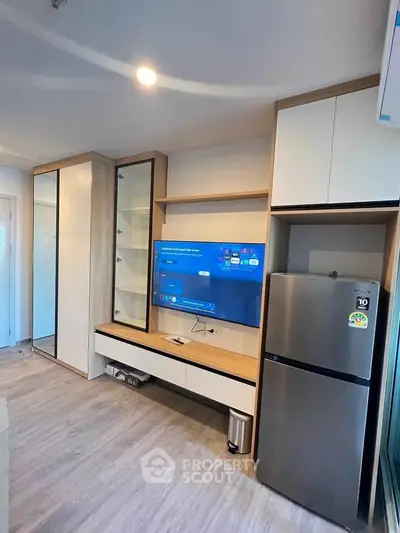 Modern living room with sleek TV setup and stainless steel fridge