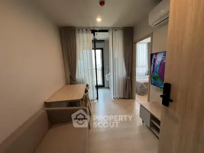 Modern living room with cozy sofa, dining table, and TV, leading to a balcony with natural light.