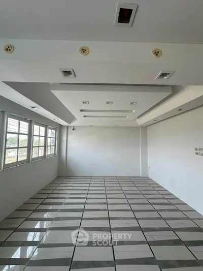 Spacious modern room with large windows and stylish ceiling design, perfect for versatile living or office space.