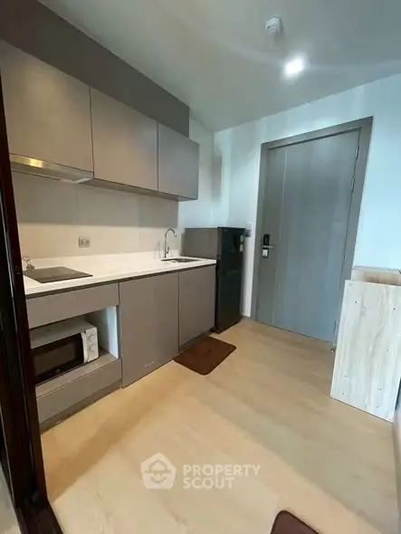 Modern compact kitchen with sleek cabinetry and integrated appliances in a stylish apartment.