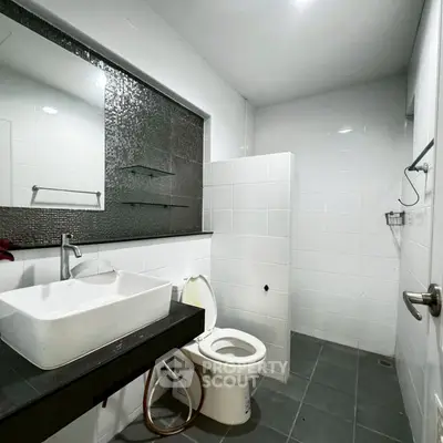 Modern bathroom with sleek sink and tiled walls in real estate property.