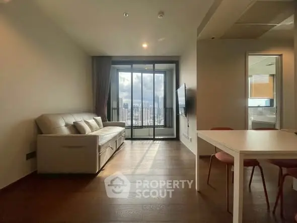 Modern living room with city view, featuring sleek furniture and floor-to-ceiling windows.
