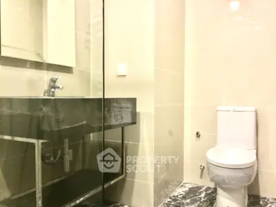 Modern bathroom with sleek fixtures and glass shower enclosure.