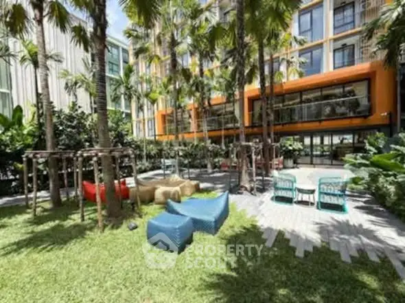 Modern apartment building with lush garden and outdoor seating area.