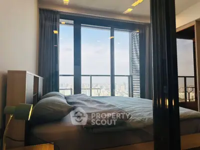 Luxurious bedroom with floor-to-ceiling windows offering stunning city views, modern decor, and ample natural light.