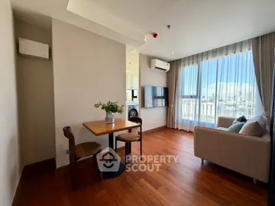 Modern living room with wooden flooring, cozy seating, and a scenic city view through large windows.