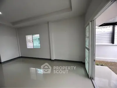 Spacious empty room with large windows and sliding door leading to outdoor area.