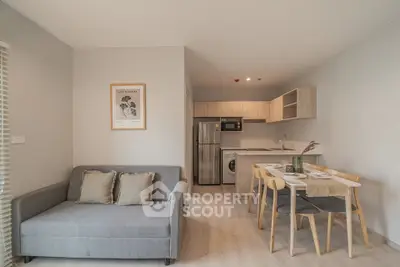 Modern open-plan living room with cozy sofa and dining area, featuring a compact kitchen with stainless steel appliances.