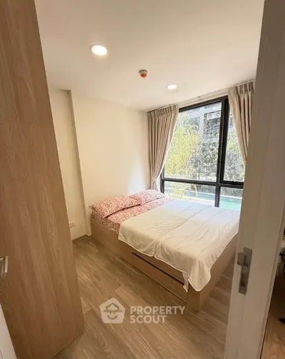 Cozy bedroom with large window and wooden flooring in modern apartment