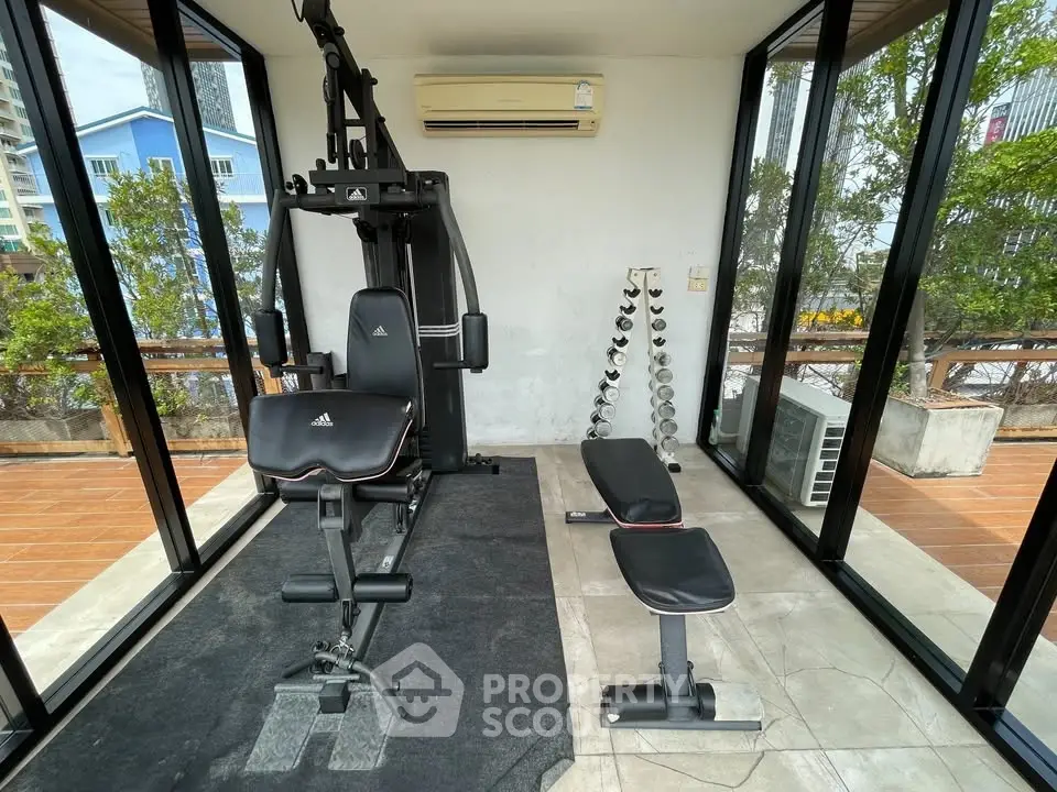 Modern home gym with exercise equipment and glass walls offering a scenic view.