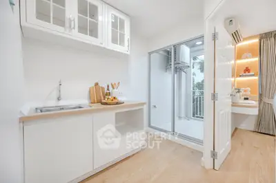 Modern kitchen with sleek white cabinets and open layout, featuring a balcony view.