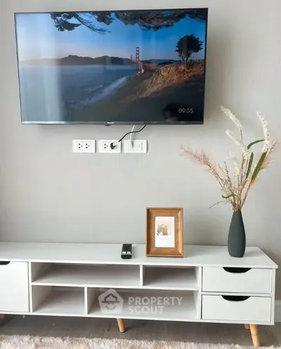 Modern living room with wall-mounted TV and stylish white console table.