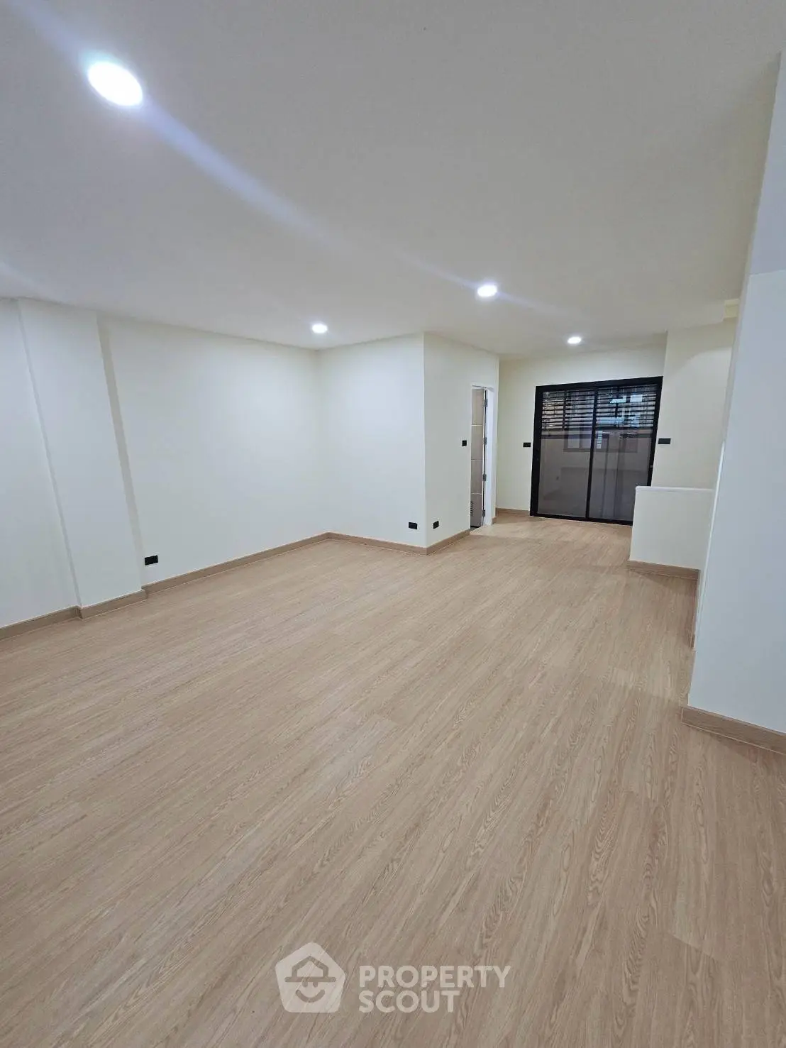 Spacious empty room with wooden flooring and modern lighting, ideal for customization.