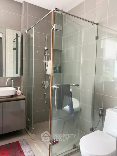 Modern bathroom with glass shower enclosure and sleek vanity in contemporary home.