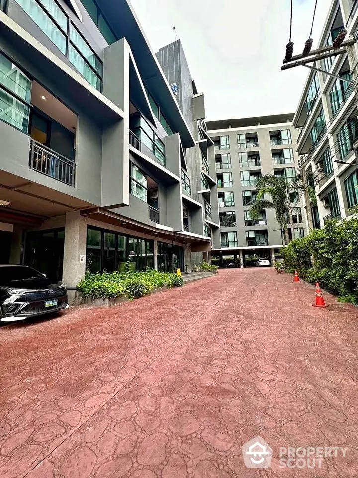 Modern apartment building exterior with spacious driveway and lush greenery