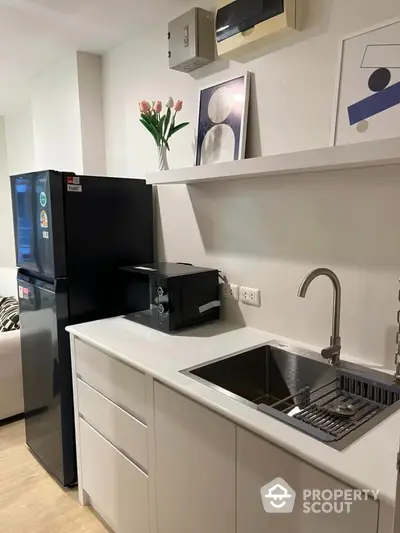 Modern kitchen with sleek design featuring black fridge and microwave