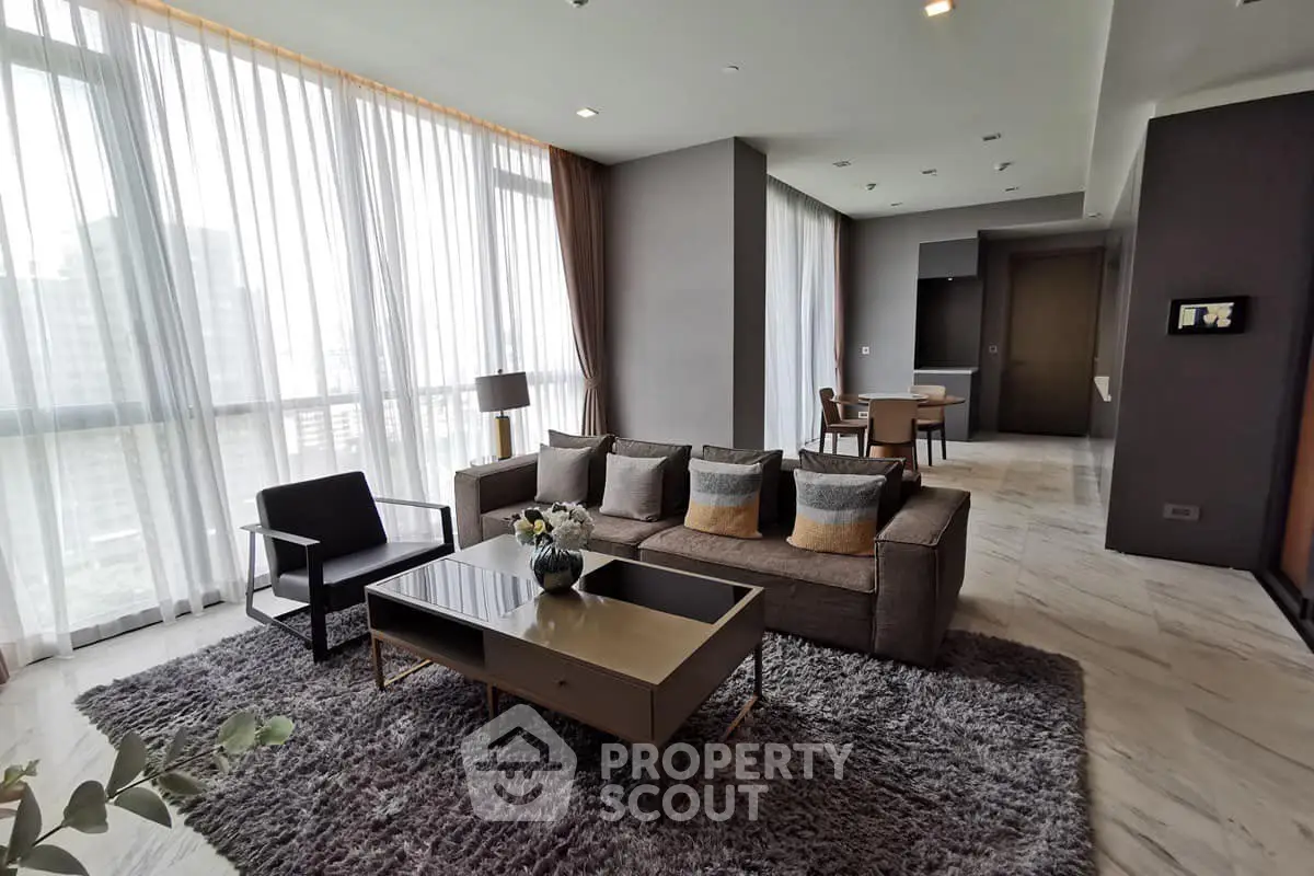 Luxurious modern living room with large windows and elegant decor in a high-rise apartment.
