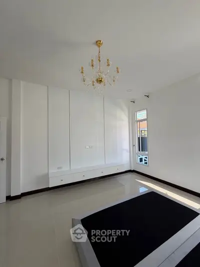 Spacious bedroom with elegant chandelier and large window for natural light