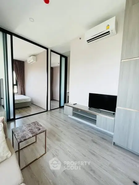 Modern living room with sleek design and air conditioning, featuring a TV and stylish furniture.