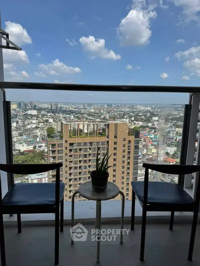 Stunning city view from a high-rise balcony with chairs and table.