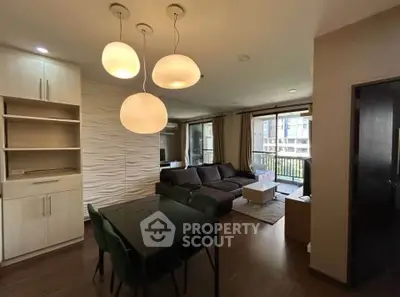 Modern living room with stylish lighting and open layout, featuring a cozy seating area and dining space.