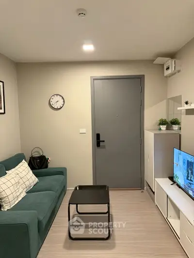 Modern living room with teal sofa, wall clock, and sleek TV setup.