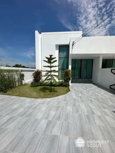 Modern minimalist white house with spacious driveway and lush garden