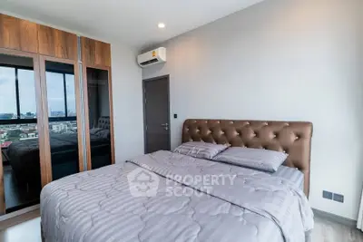 Modern bedroom with stylish decor and city view from window, featuring a cozy bed and sleek wardrobe.