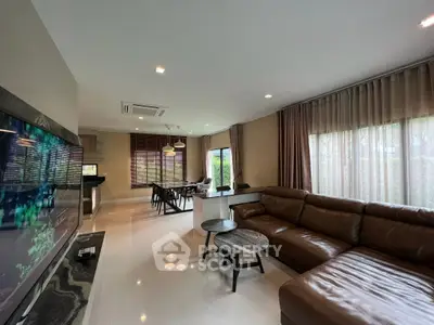 Spacious modern living room with leather sofa and large windows offering natural light.