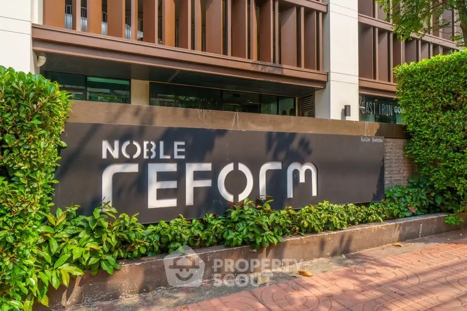 Modern building entrance with stylish signage and lush greenery