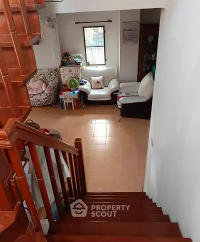 Charming living room with cozy seating and wooden staircase in a welcoming home.