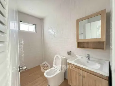 Modern bathroom with sleek white tiles and wooden vanity in a bright, minimalist design.